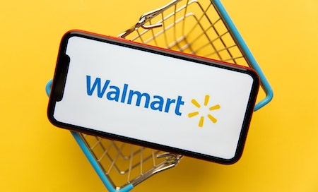 Walmart app on smartphone in the middle of a shopping cart, yellow background 